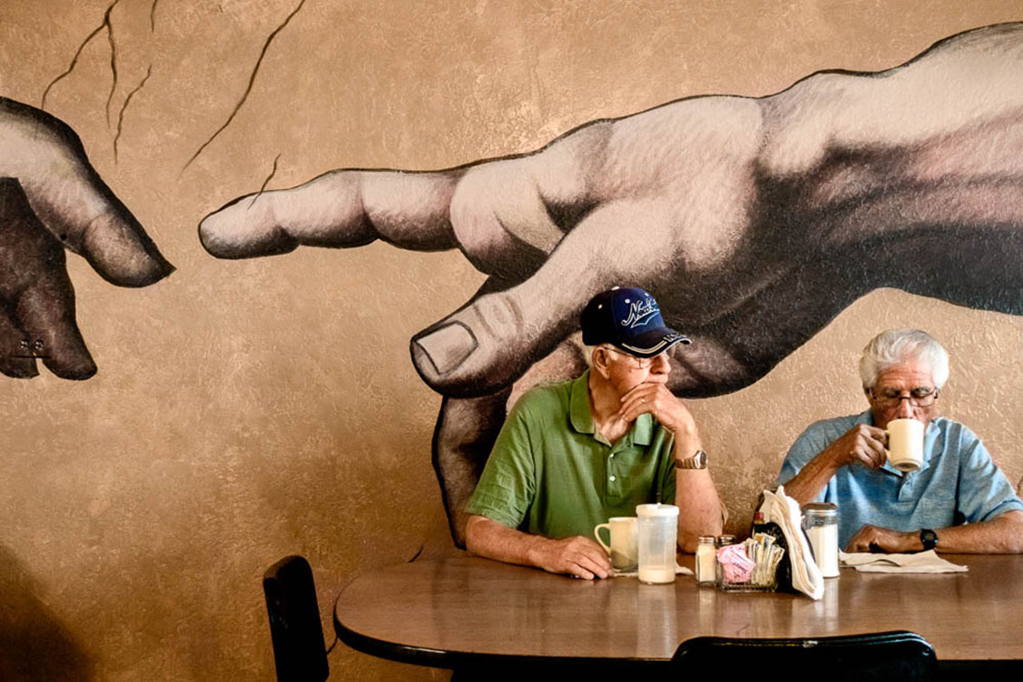 Adobe wall-painted hand of God and Adam in restaurant
