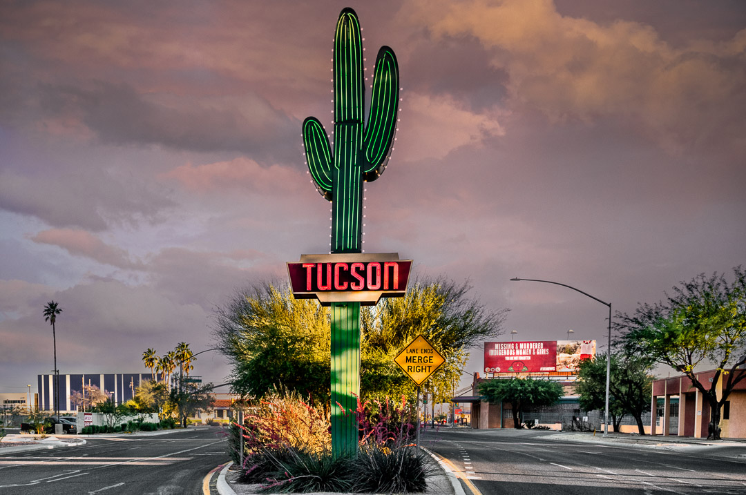 Urbanwalls 11.240519 AZ Neon saguaro in middle of large road in Tuscon with storm clouds in background.