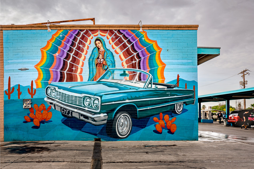 Urbanwalls 3. 211121_AZ_17_20 Mural of lowrider car on brick wall with Virgin Mary, cactus, and UFO. Car wash in background. South Tuscon.